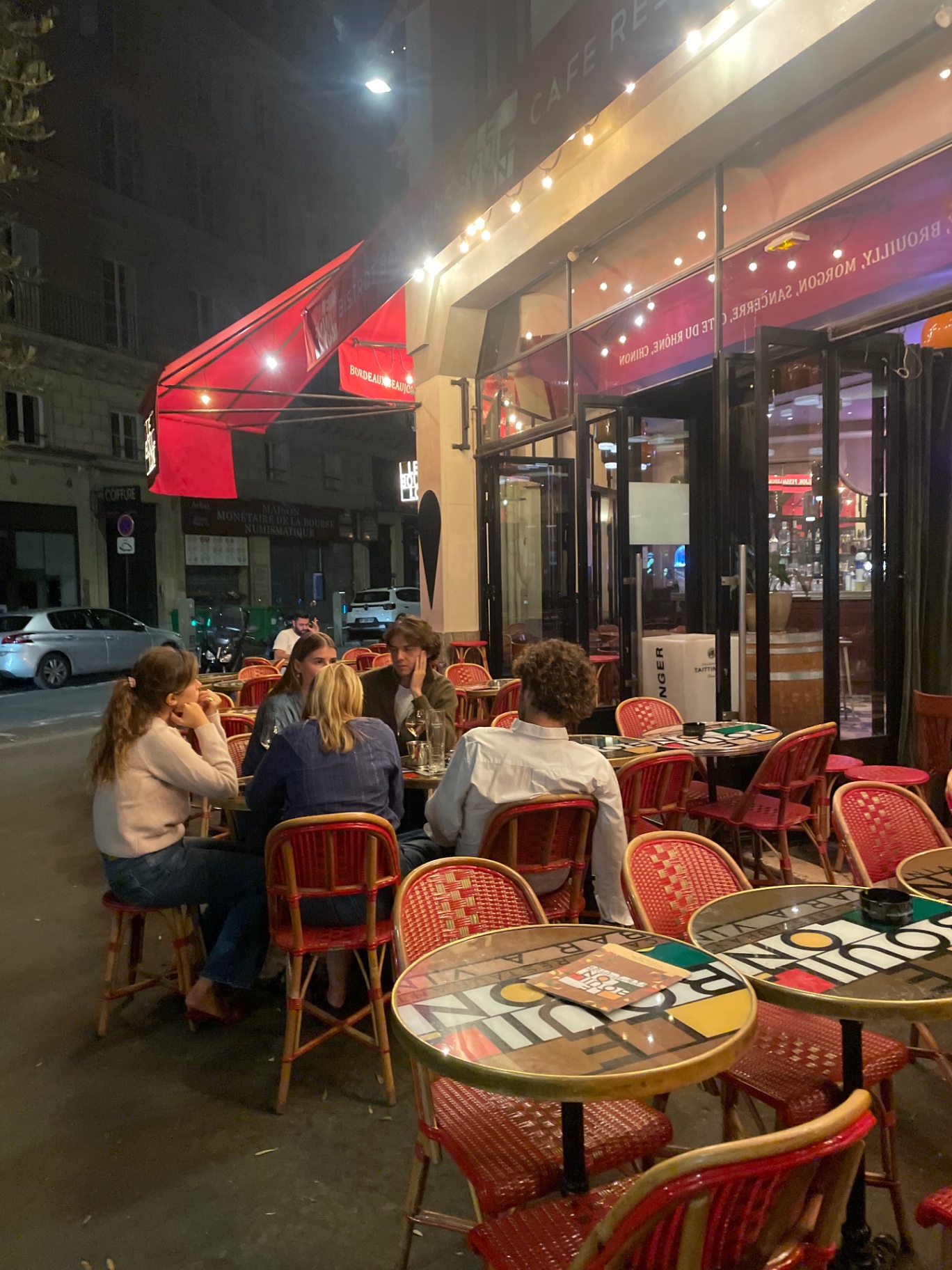 Convives en terrasse devant la façade rouge